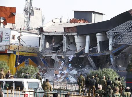 Security personnel deployed outside an automobile showroom, which is being demolished during an anti-encroachment drive, in Jammu on Saturday, Feb. 11, 2023.