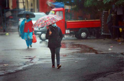 A woman takes umbrella cover during rains in Jammu on Wednesday.