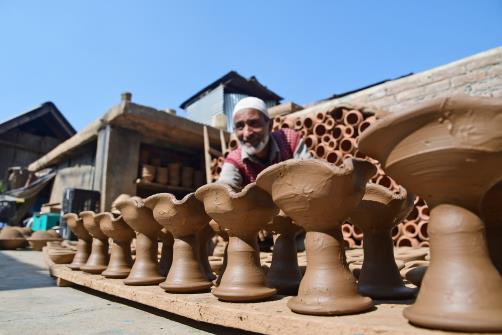 A potter Abdul Salam Kumar arranges the earthen lamps to dry at his workshop ahead of Diwali festival, on the outskirts of Srinagar on Sunday. 