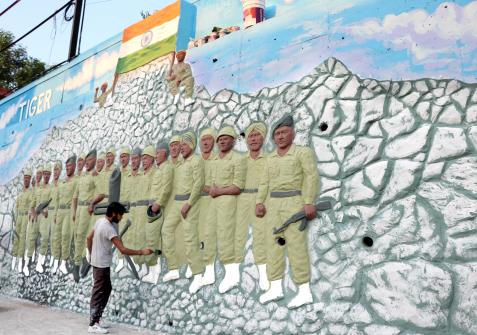An artist gives the finishing touch to a wall mural depicting Tiger Hill and Indian army soldiers, ahead of Kargil Vijay Diwas, in Jammu on Tuesday.