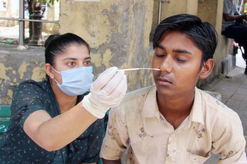 A healthcare worker collects a nasal swab sample of a man for the COVID-19 testing, amid a recent surge in the Coronavirus cases, in Jammu on Tuesday. 