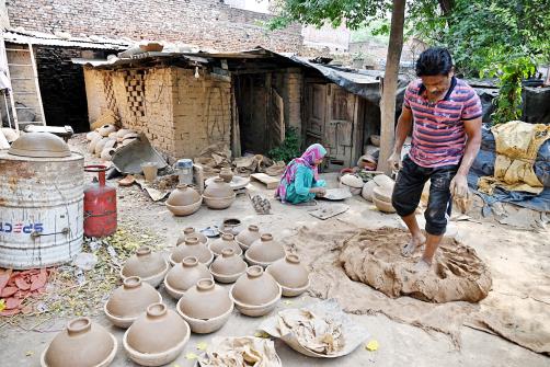 A potter mixing clay for making earthen pots at bus stand in Jammu on Friday.